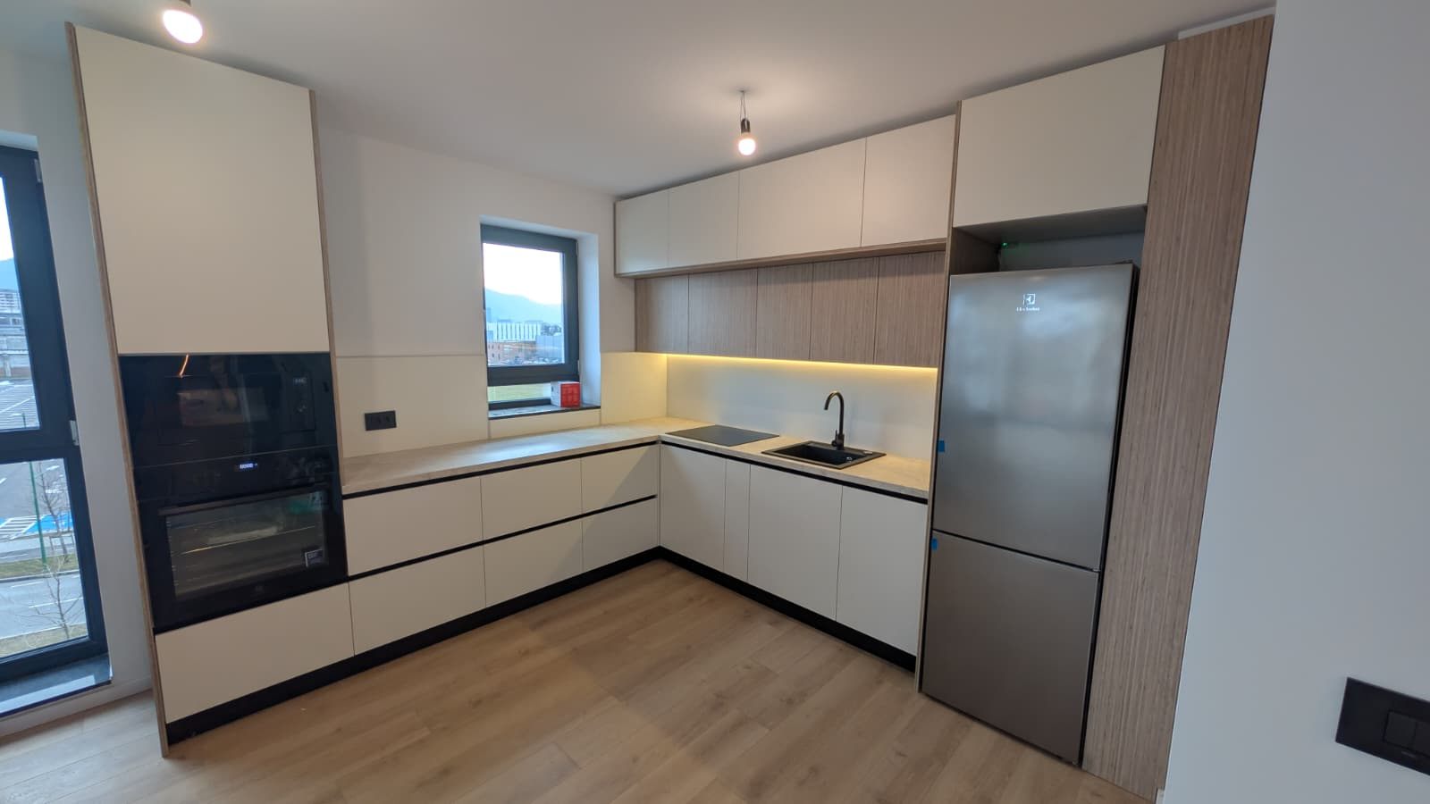 Frigider inox încadrat într-o coloană de nuc, lângă fronturi crem mate